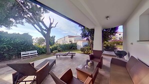 An outdoor patio with wicker furniture, a table, and a bench. - Villa Vora a mar in Calafell (Calafell)
