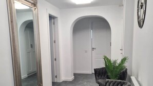 A hallway with a large mirror, two plush chairs, a radiator, and a ceiling light. - Villa Vora a mar in Calafell (Calafell)
