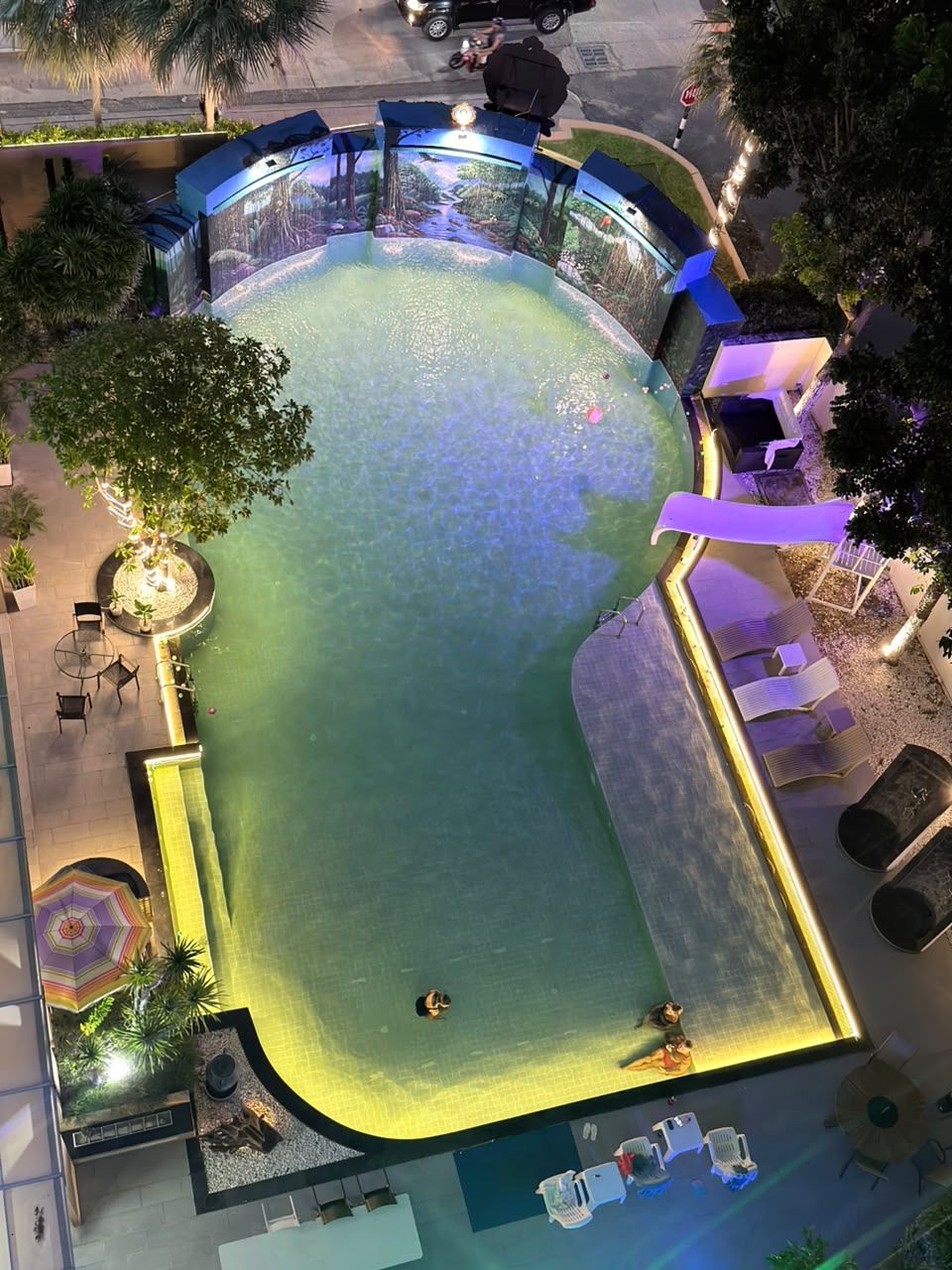An outdoor swimming pool with a curved design, surrounded by lounge chairs and a seating area.