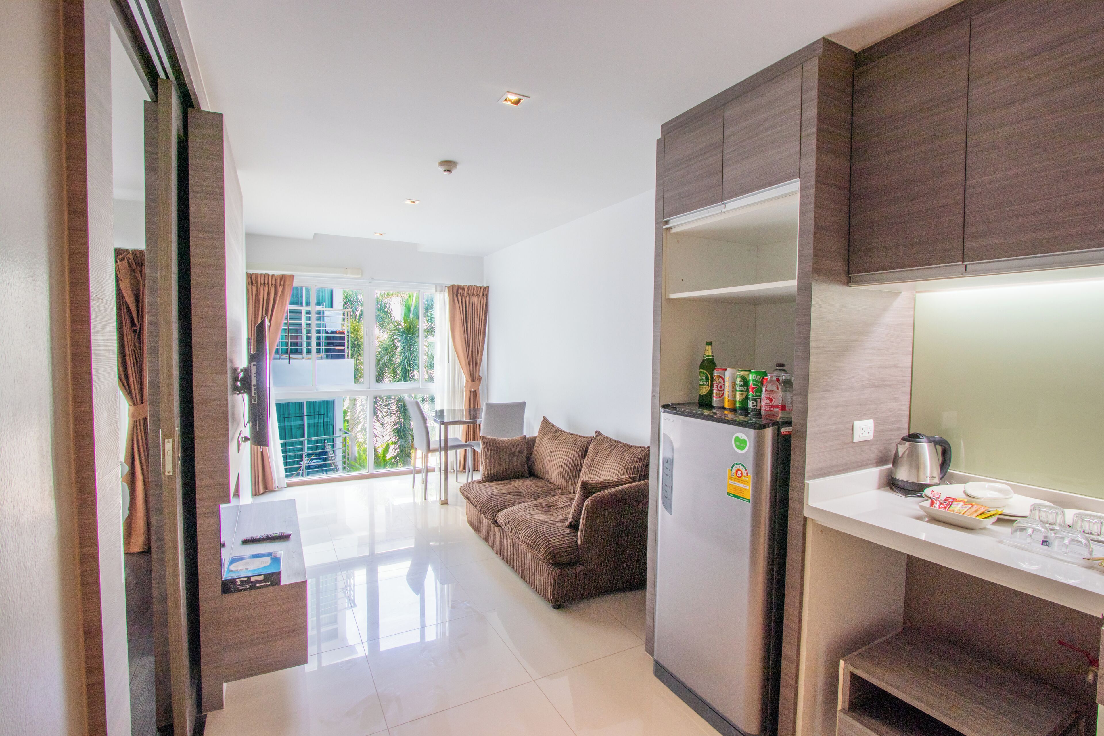 A compact kitchen with a refrigerator, a coffee maker, and a dining area with a table and chairs.