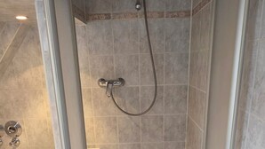 Une salle de bain moderne dotée d’une douche à l’italienne, d’une baignoire séparée et d’un revêtement de sol carrelé.
