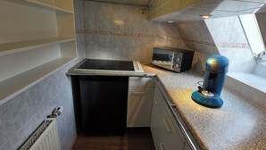 Une cuisine compacte équipée d’un four à micro-ondes encastré, d’une petite cuisinière et d’une machine à café.