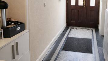A hallway with a wooden door, a keycard reader, a radiator, and a patterned rug.