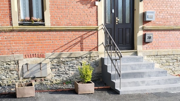 A brick building with a black door, a small set of steps leading to the entrance, and a mailbox with the number 28. - Hotel Kremer  (Buechenbeuren)