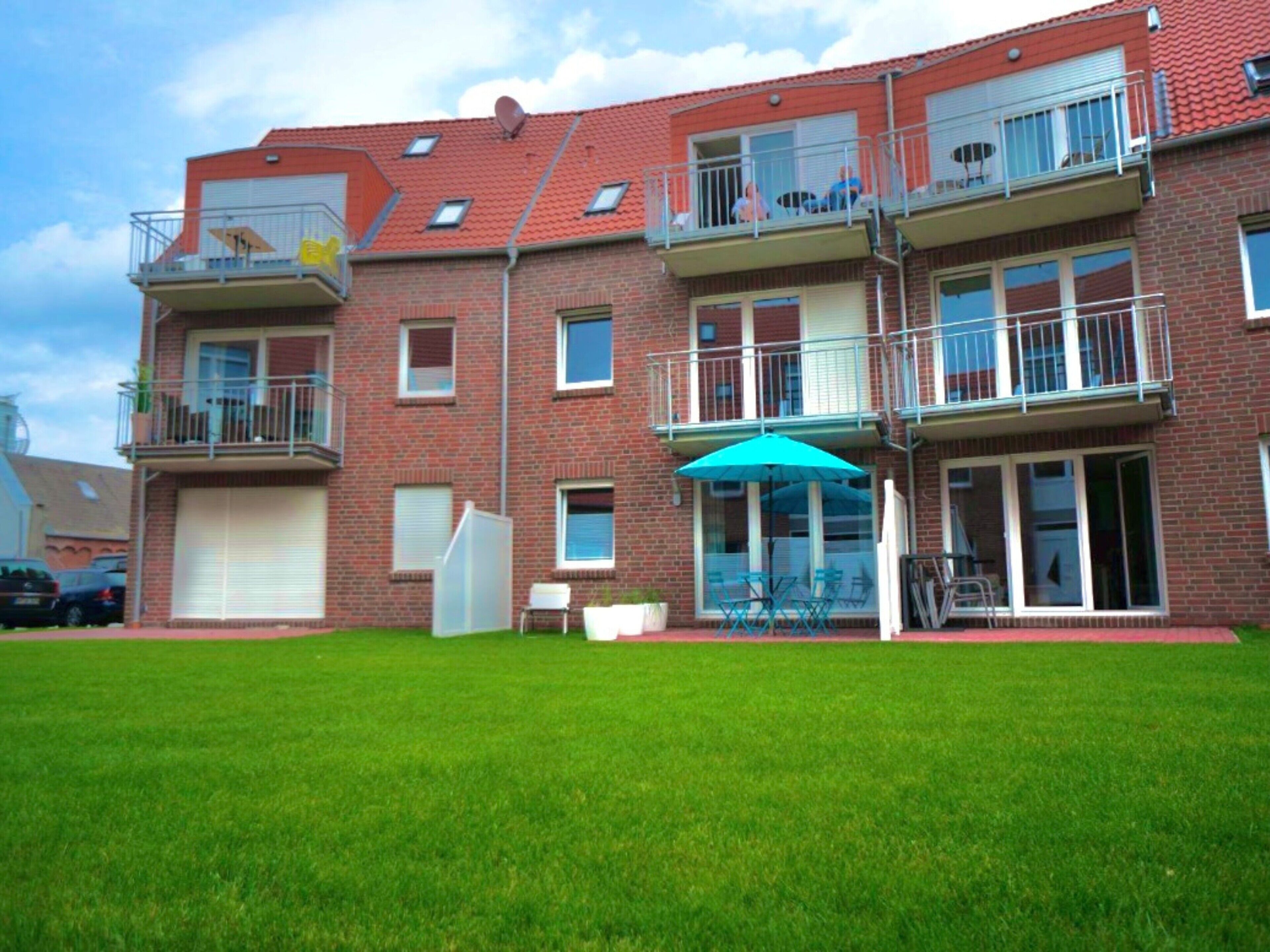 Ein mehrstöckiges Wohngebäude mit Balkonen, einer Garage und einem gepflegten Rasen.