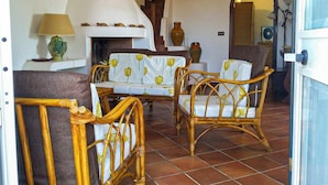 A living room with wicker furniture, a white sofa with yellow tulip cushions, a lamp, and a fireplace. - Villa Sofia (Manduria)