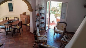 A dining area with a wooden table and chairs, a ceiling fan, and a glass shelving unit. - Villa Sofia (Manduria)