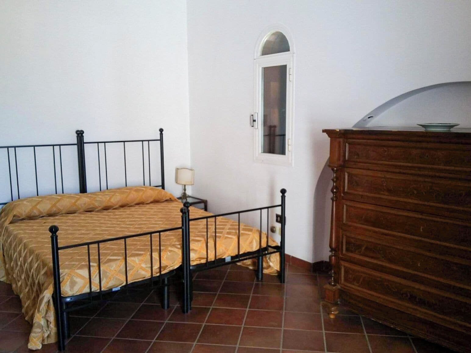 Un dormitorio con cama, cómoda, mesita de noche y ventana.