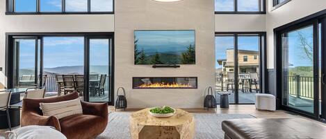 Un salón amplio con chimenea, ventanas grandes y vistas al exterior.