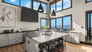 Une cuisine moderne dotée d’un grand îlot central, de tabourets de bar et offrant une vue sur les montagnes.