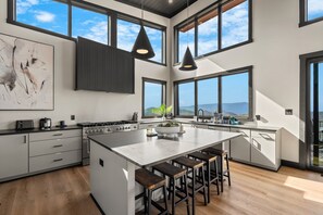 Una cocina moderna con una isla grande, taburetes de bar y vistas a las montañas.