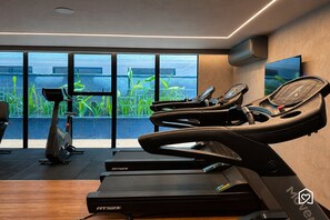 Ein modernes Fitnessstudio mit Laufbändern, einem Ergometer und einem Fernsehbildschirm.