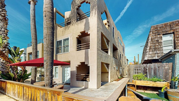 Un edificio moderno con un diseño arquitectónico único, que presenta un balcón y una zona de terraza de madera.