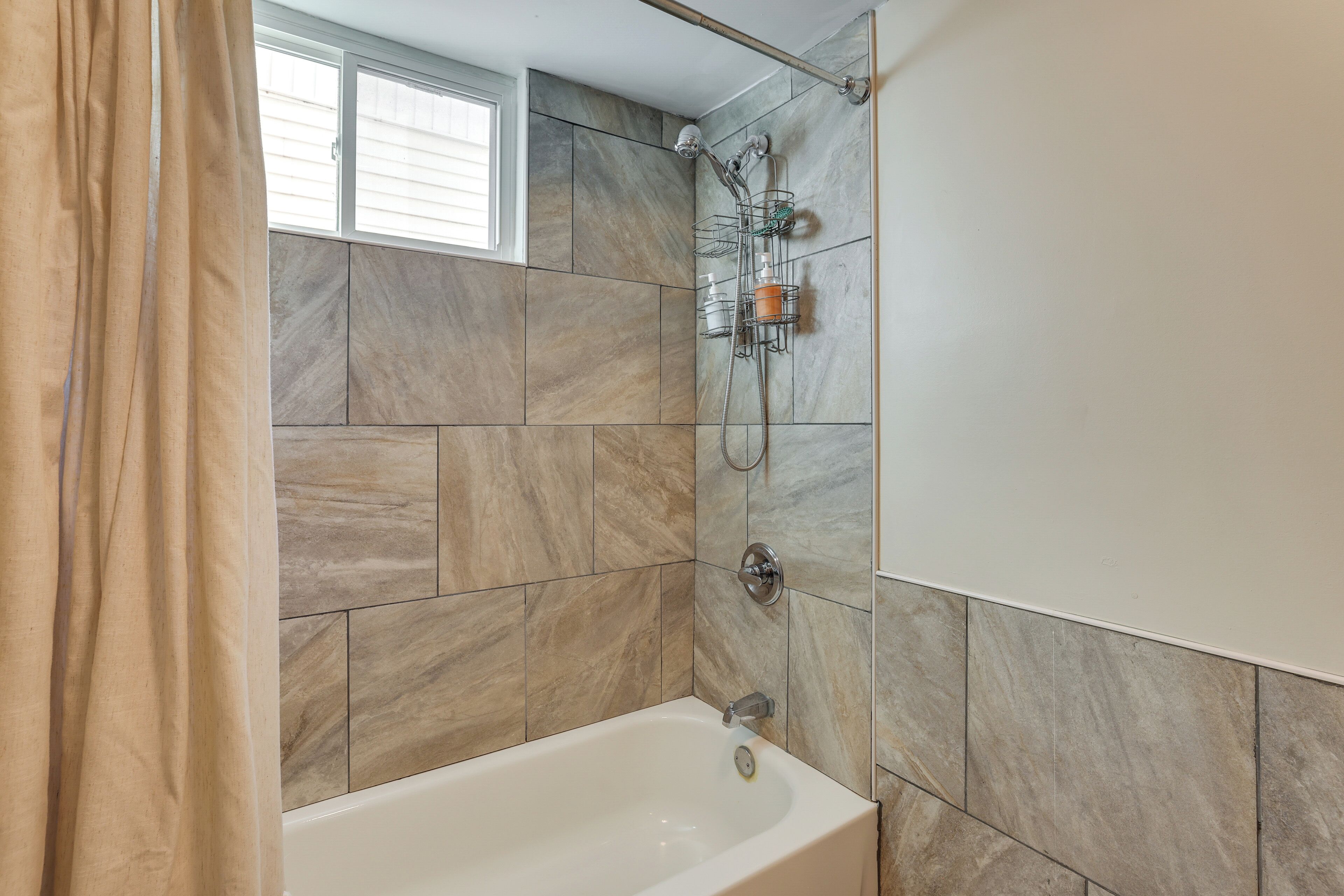 A bathroom with a bathtub, shower, and tiled walls.