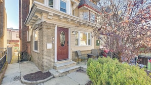 A two-story townhouse with a red front door, a small front porch, and a brick exterior. - Pet Friendly! 3-story Home Near Cobbs Creek Park! (Philadelphia)