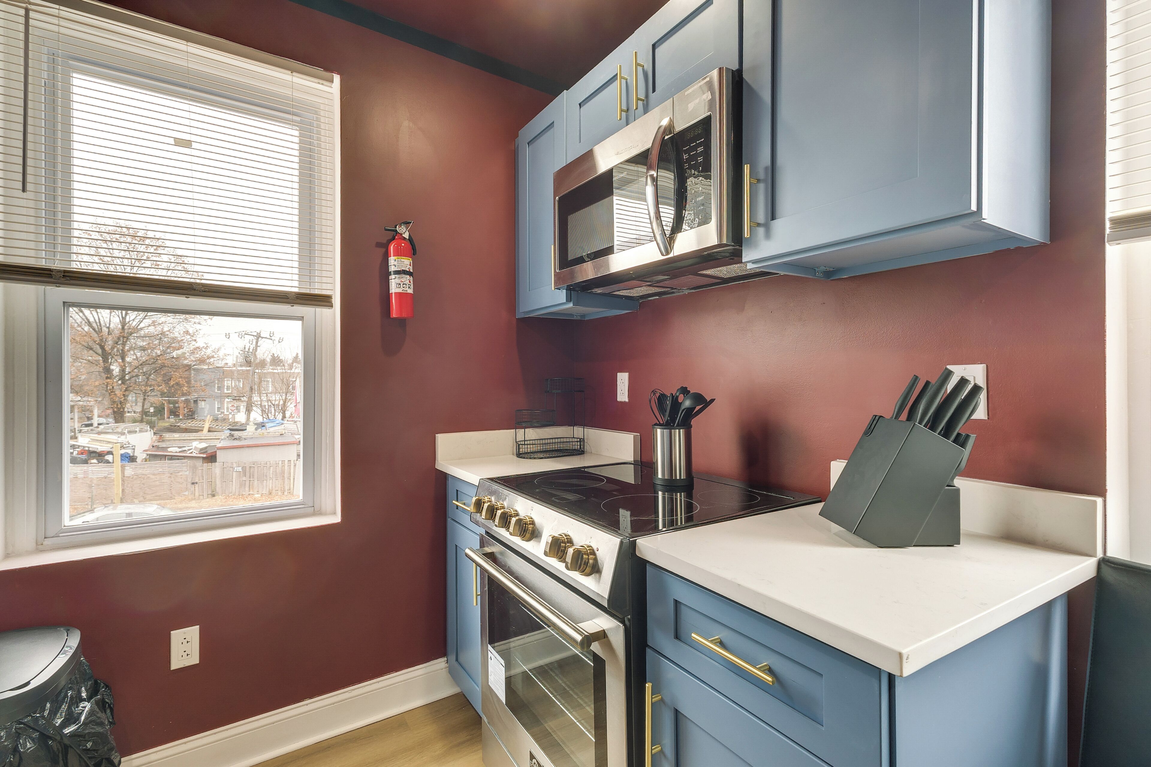 A kitchen with blue cabinets, a stainless steel microwave, a gas stove, and an oven.