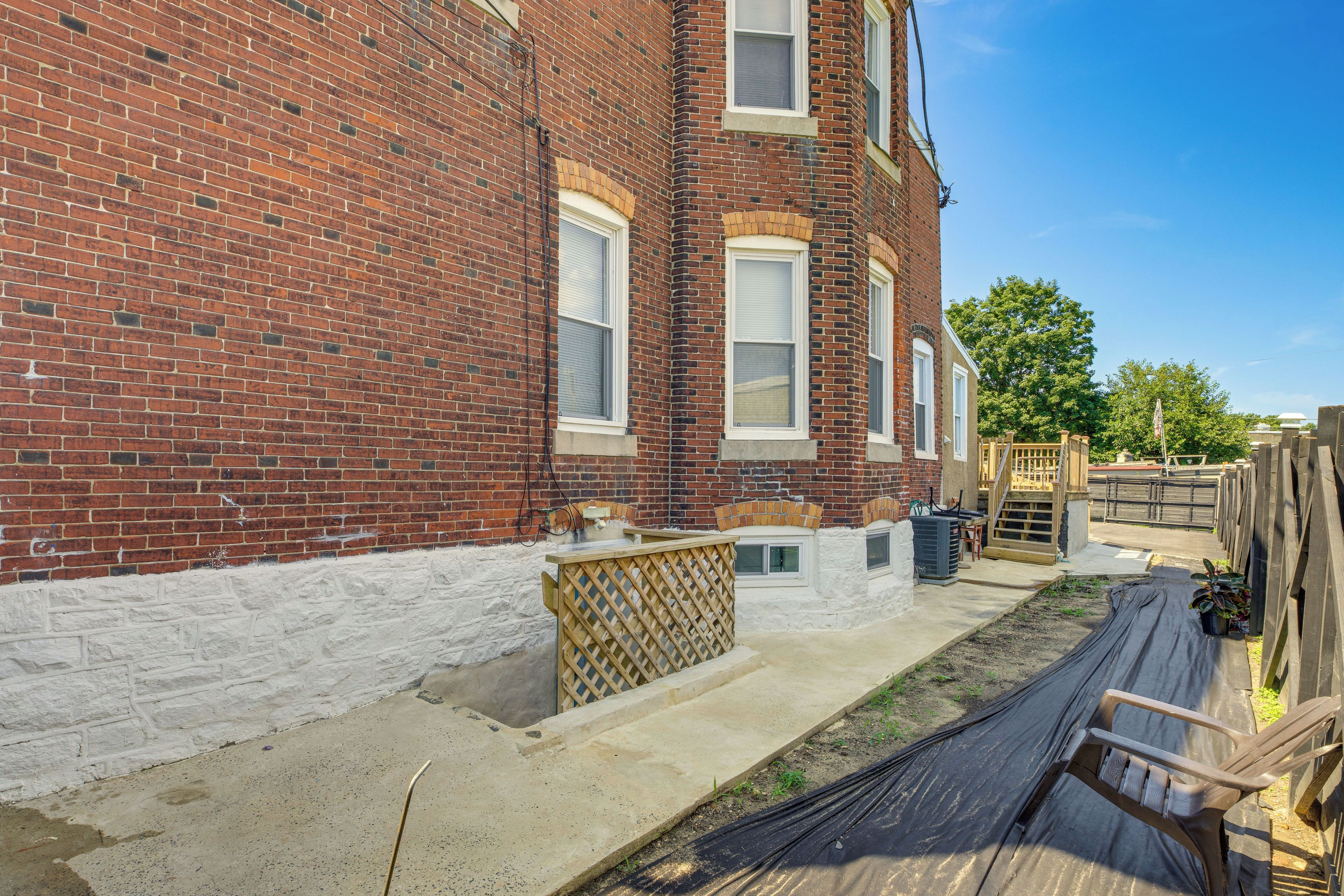 A brick building with a concrete patio, a wooden fence, and a clear blue sky.