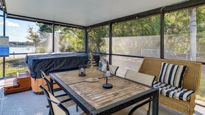 Una veranda riparata con tavolo, sedie, divano e un letto.
