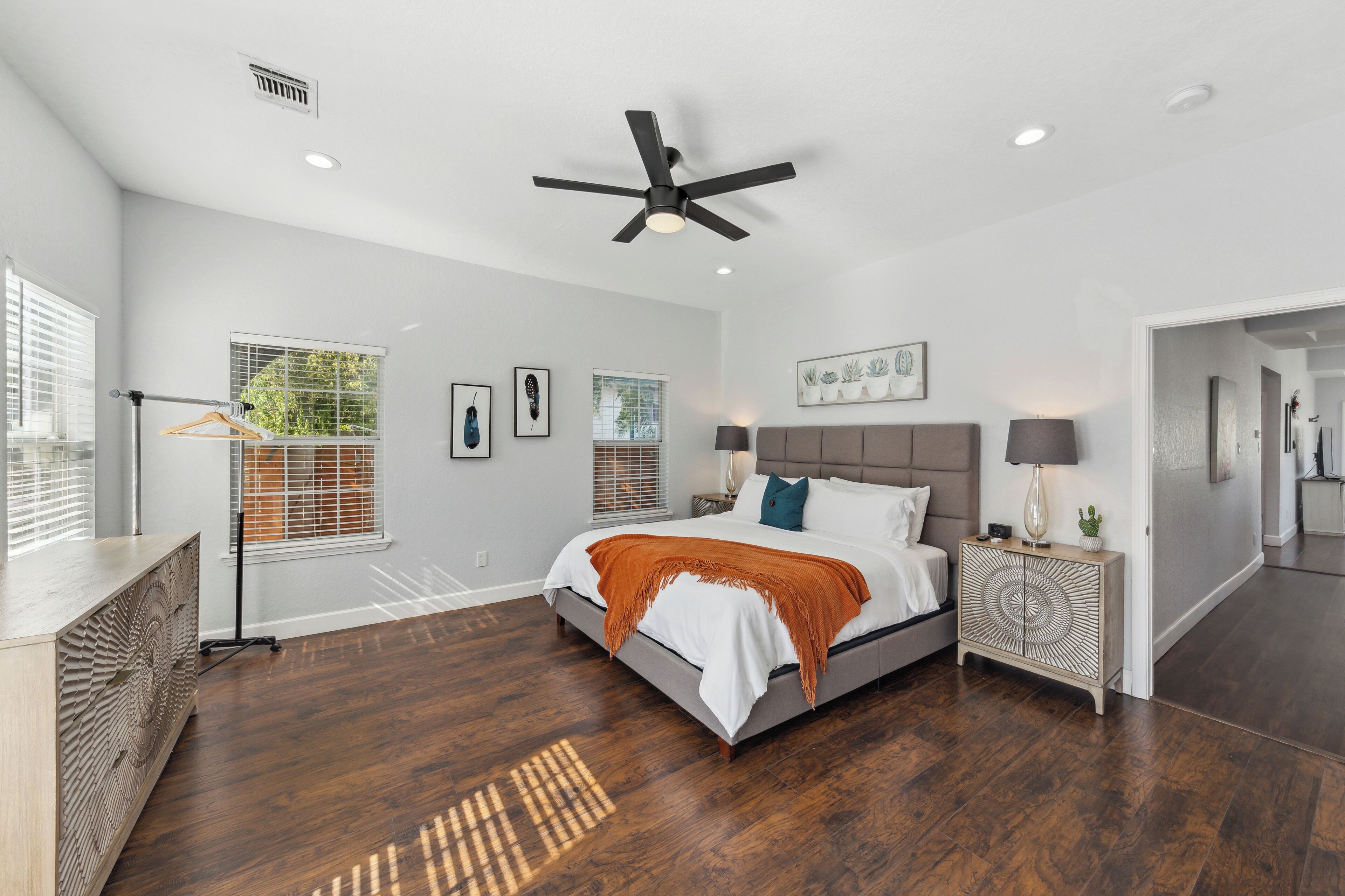A bedroom with a bed, bedside tables, a ceiling fan, and a window with blinds.