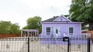 A purple house with a black metal fence, a number 611 sign, and a covered porch. - Walk to Alamodome! Stylish Home w/ Private Parking (San Antonio)