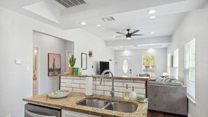 A modern kitchen with granite countertops, stainless steel appliances, and a grey sofa in the adjacent living area. - Walk to Alamodome! Stylish Home w/ Private Parking (San Antonio)