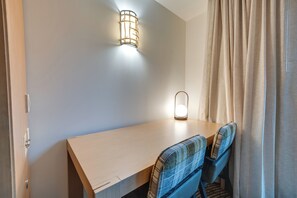 A small, neatly arranged room with a wooden desk, two plaid chairs, a wall-mounted light fixture, and a curtain on the right. - Beautiful Studio in Suncadia Resort (Cle Elum)