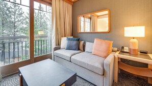 A hotel room with a sofa, a desk, a lamp, and a view of trees through large windows. - Beautiful Studio in Suncadia Resort (Cle Elum)