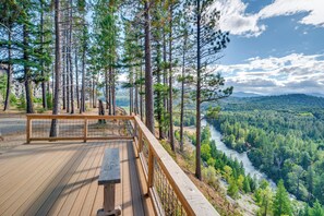 En träveranda med utsikt över en flod och en skog.