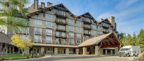 A multi-story hotel with a stone facade, multiple balconies, and a covered entrance.