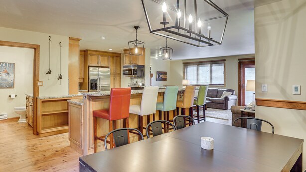 A spacious kitchen with wooden cabinets, a stainless steel refrigerator, and a dining area with a large table and colorful chairs. - 2 Mtn-view Decks! East Vail Unit By Trails & Bus (Vail)
