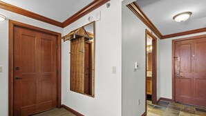 A hallway with wooden doors, a coat rack, and a tiled floor. - Valley-view Unit in Everline Resort: Premier Perks (Olympic Valley)