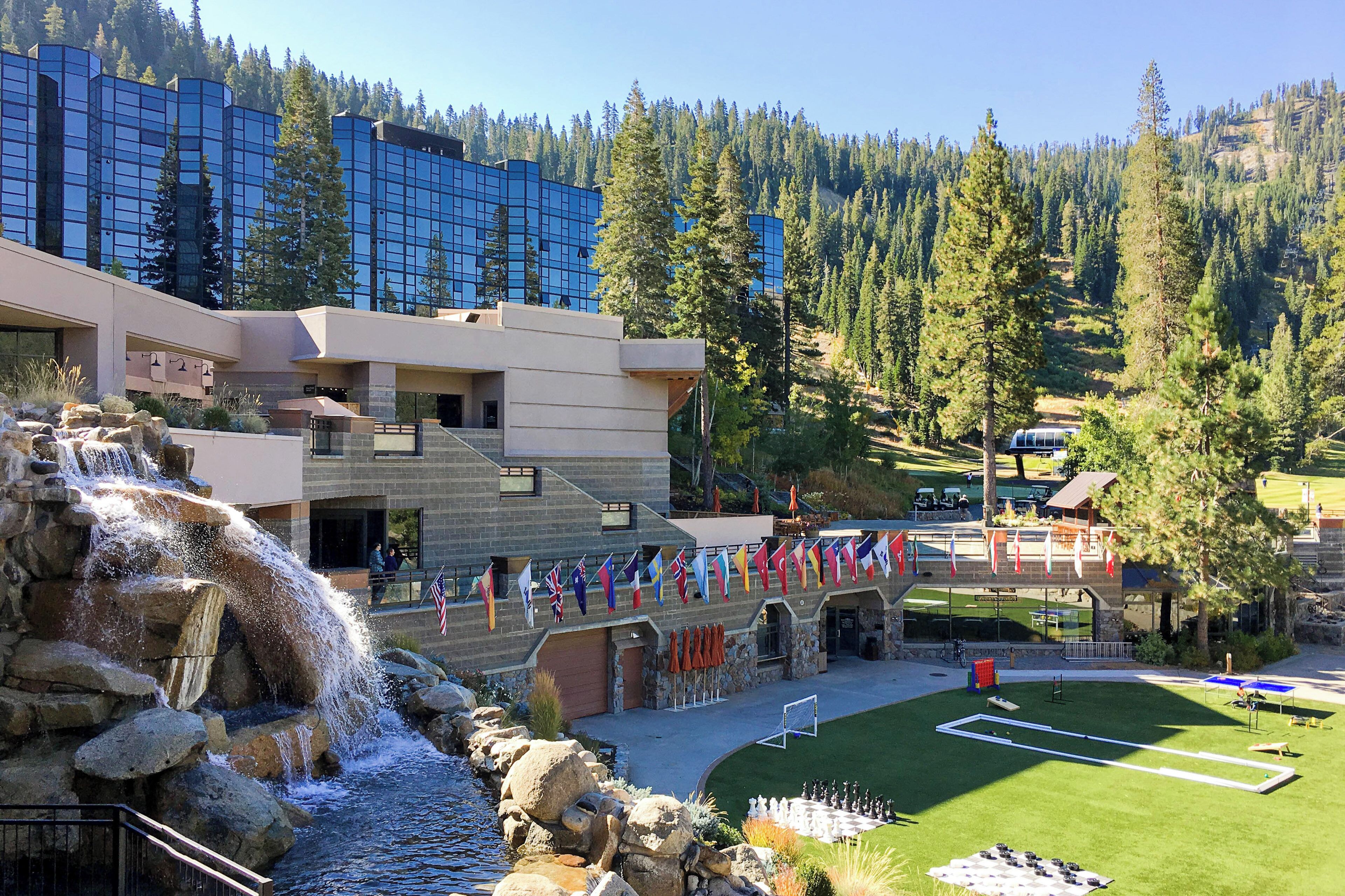 A hotel with a waterfall, a pool, and a tennis court.