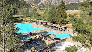 A resort with multiple swimming pools, lounge areas, and a mountainous backdrop. - Pool, Hot Tub & Golf: Everline Resort Corner Suite (Olympic Valley)
