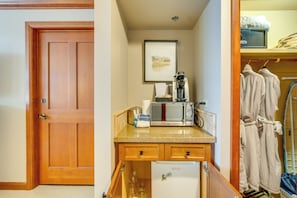 Eine kleine Küchenzeile mit Mikrowelle, Kaffeemaschine und Kühlschrank.