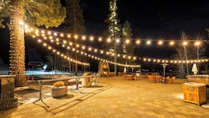 Een terras buiten met lichtjes, zitplaatsen en een vuurkorf.