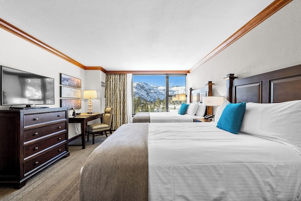 Une chambre d’hôtel avec deux lits, un bureau, une télévision et une vue sur les montagnes.