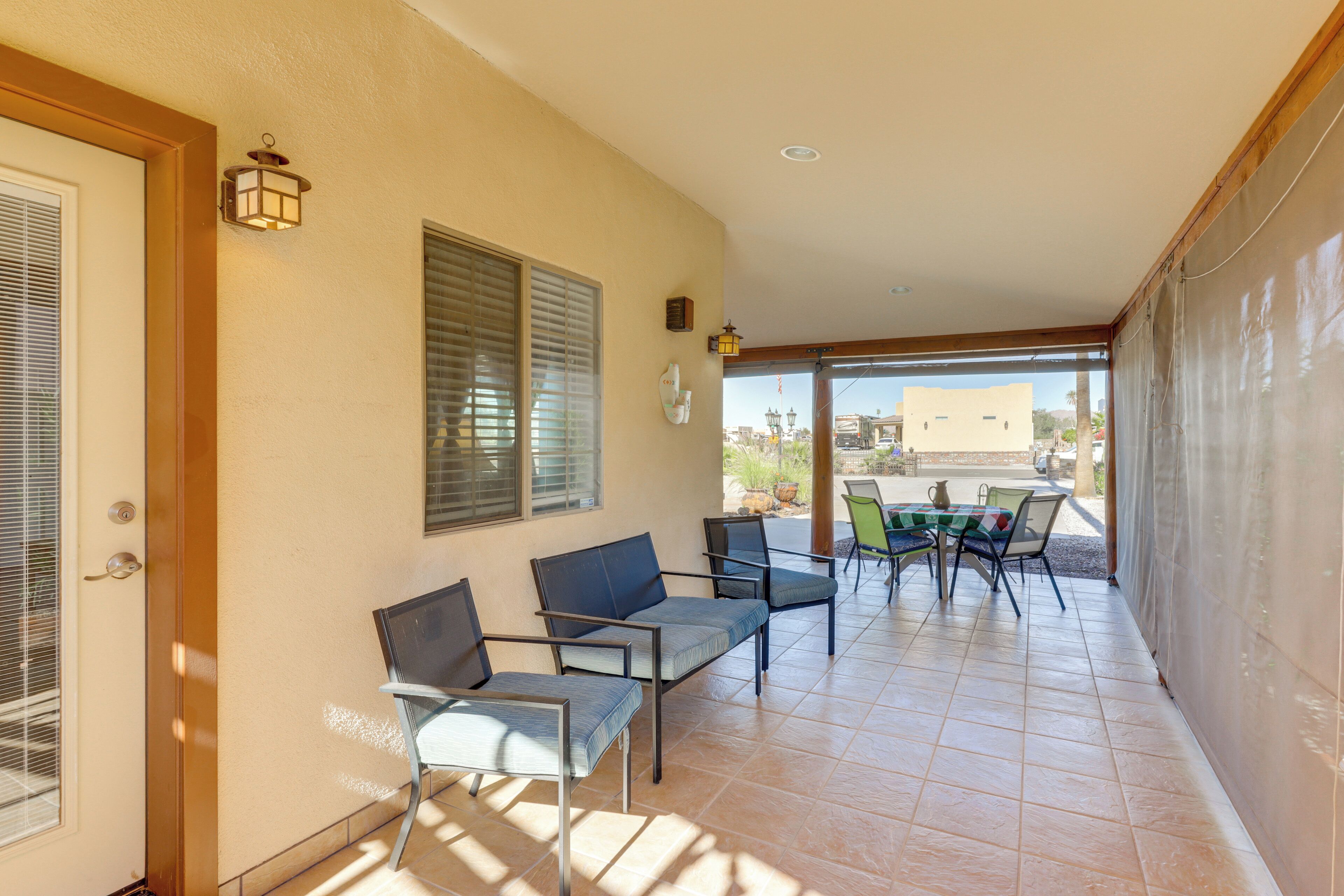 A covered patio with outdoor seating, a door with a window, and a view of the outside.