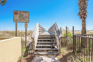 Una scala di legno conduce a una spiaggia, con un cartello che indica 'No Dogs Allowed'.