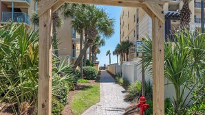 A pathway flanked by palm trees and a red fire hydrant, leading to a building with balconies. - 2 BR Condo w/ Shared Pool & Beach Access (Fort Walton Beach)