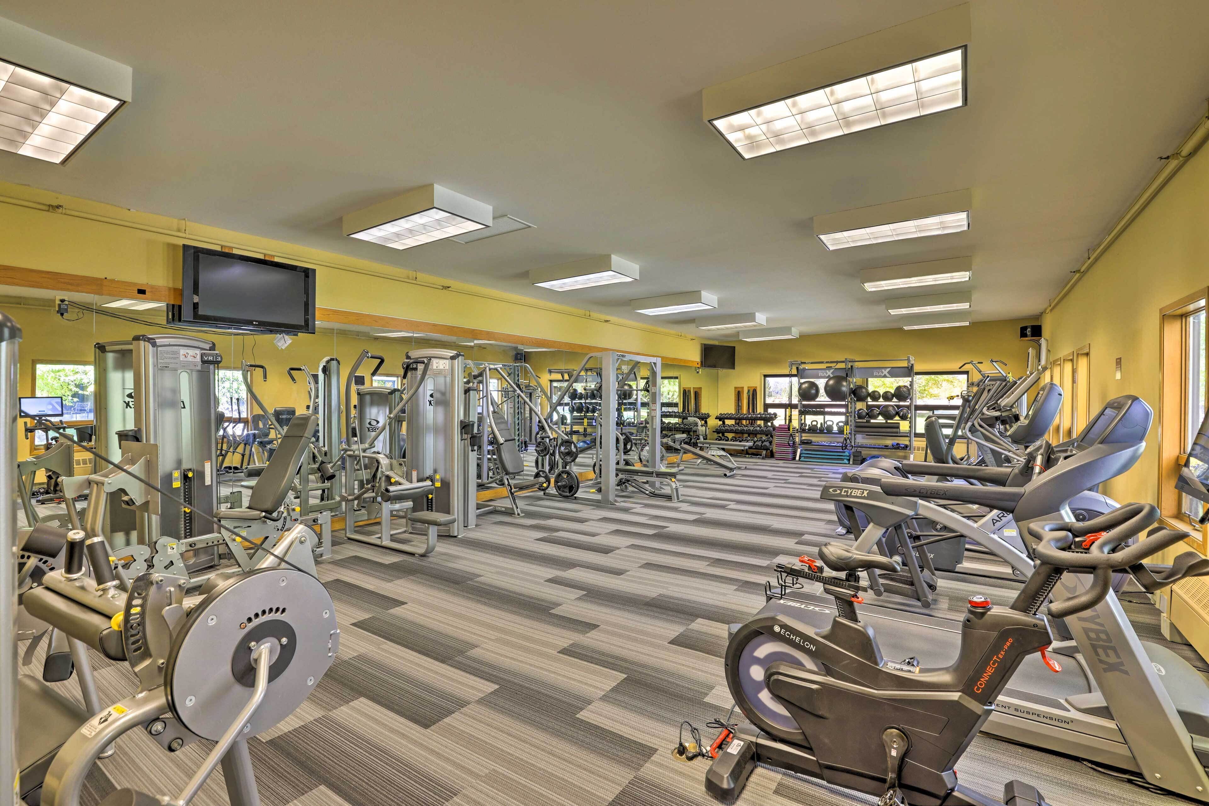 Une salle de sport équipée de divers appareils d’exercice, d’un téléviseur et d’un miroir.
