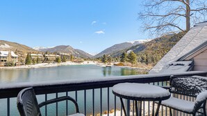 Ein Balkon mit schneebedeckten Stühlen und Blick auf einen See und Berge.
