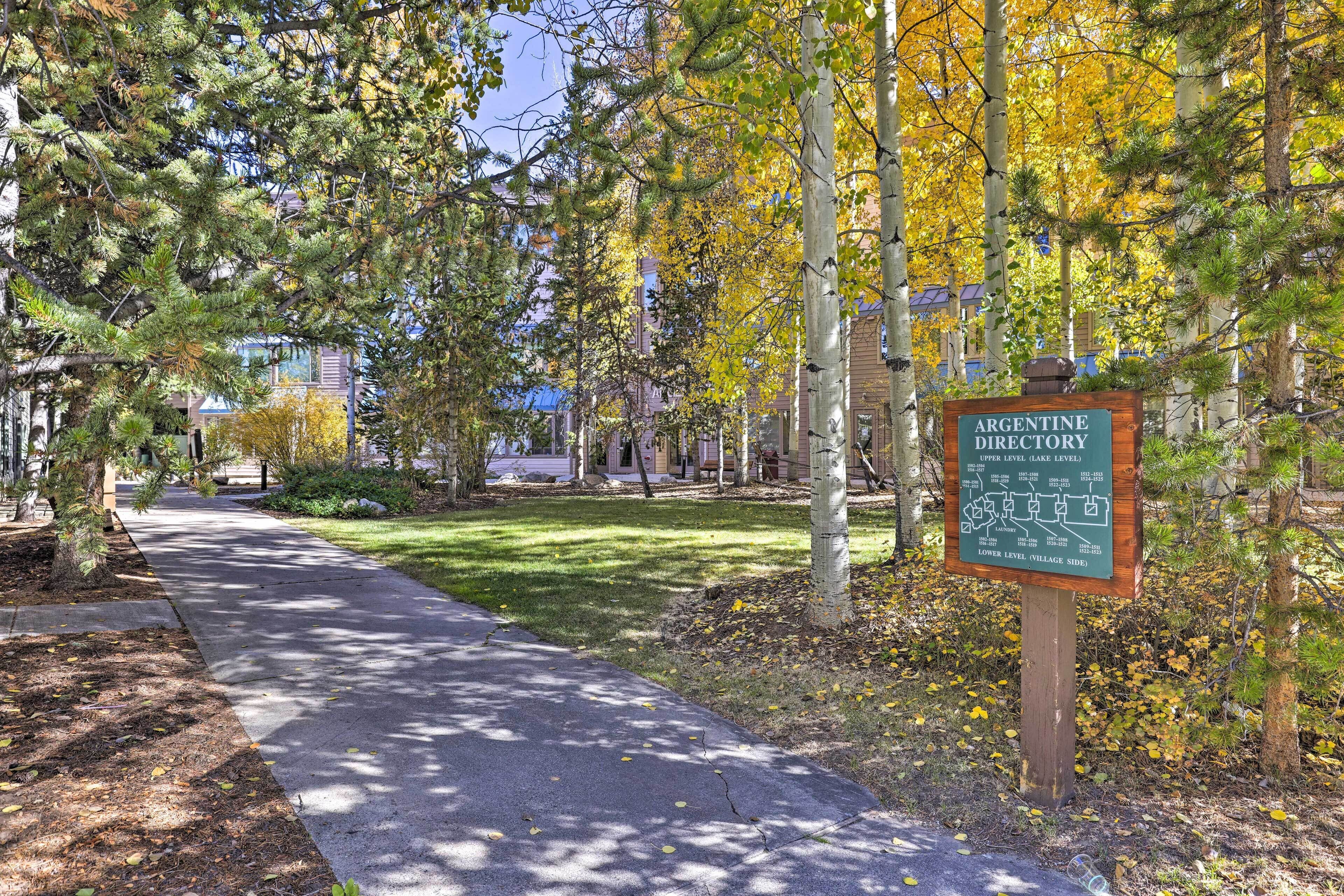 A pathway leading to a sign labeled 'Argentine Directory' with a map, surrounded by trees and a grassy area.