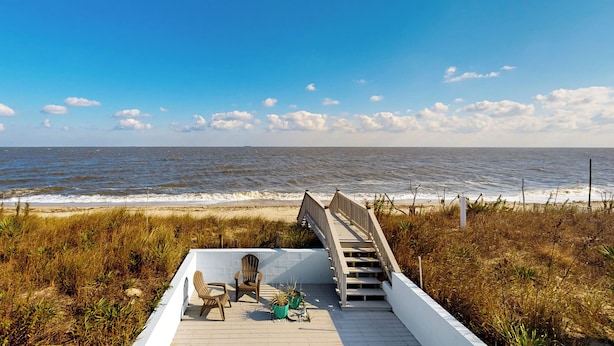 Eine Holzterrasse mit einer Treppe, die zum Strand führt.