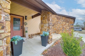 A stone exterior with a wooden door and two planters with green foliage. - Tulsa Area Home w/ Fenced Yard: Pets Welcome! (Tulsa)