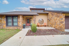 A stone house with a front porch, a garage, and a small garden area. - Tulsa Area Home w/ Fenced Yard: Pets Welcome! (Tulsa)