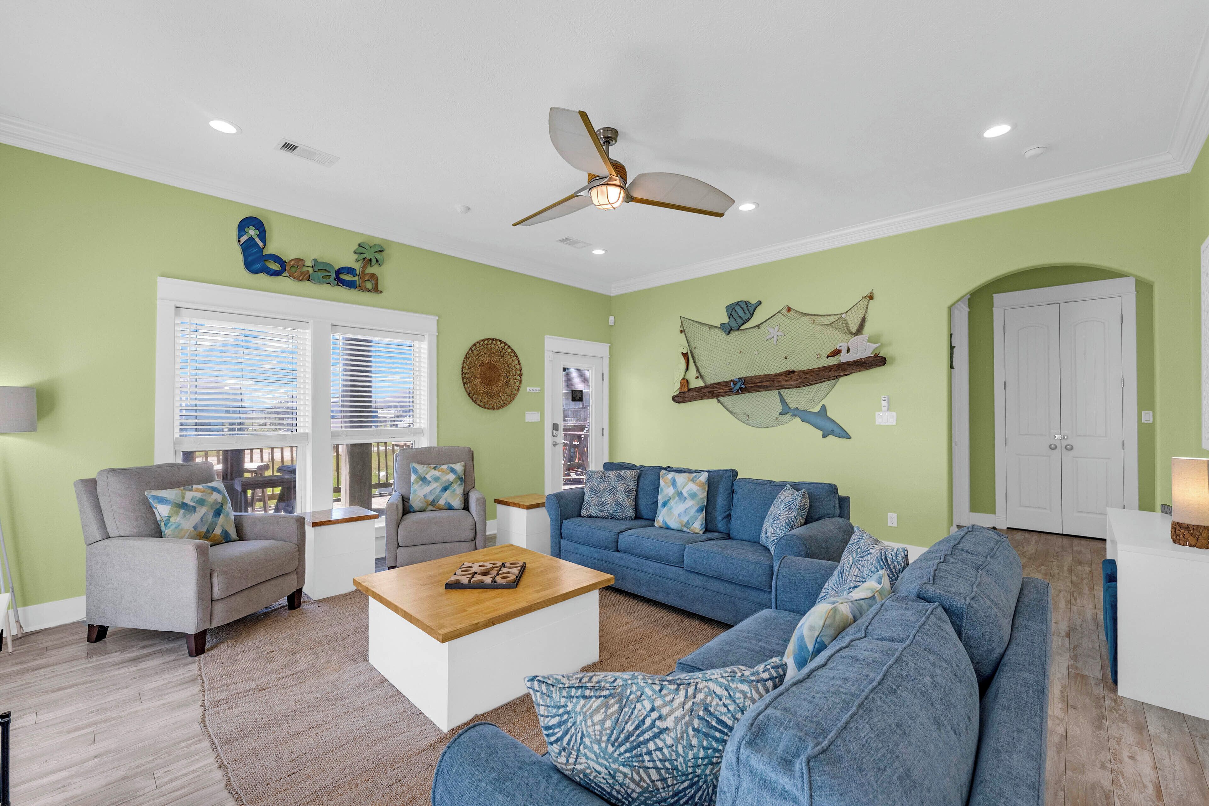 A living room with a ceiling fan, a wooden coffee table, a blue sofa, and a grey armchair.