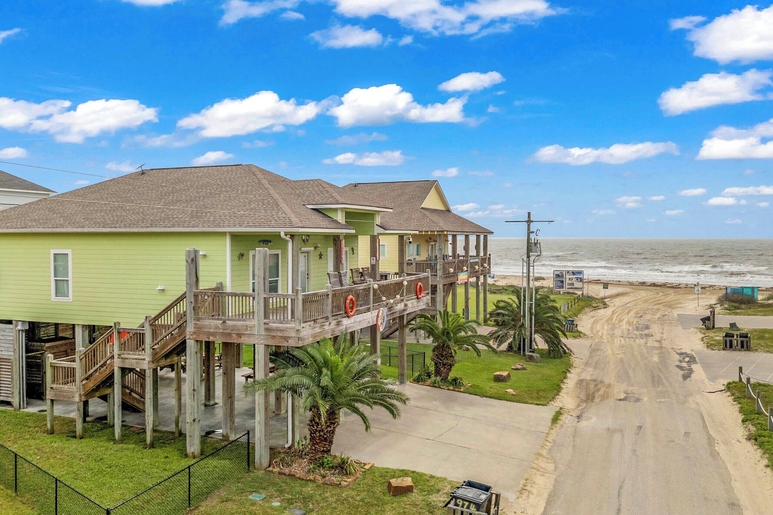 A beachfront property with a wooden deck, a balcony, and a view of the ocean.