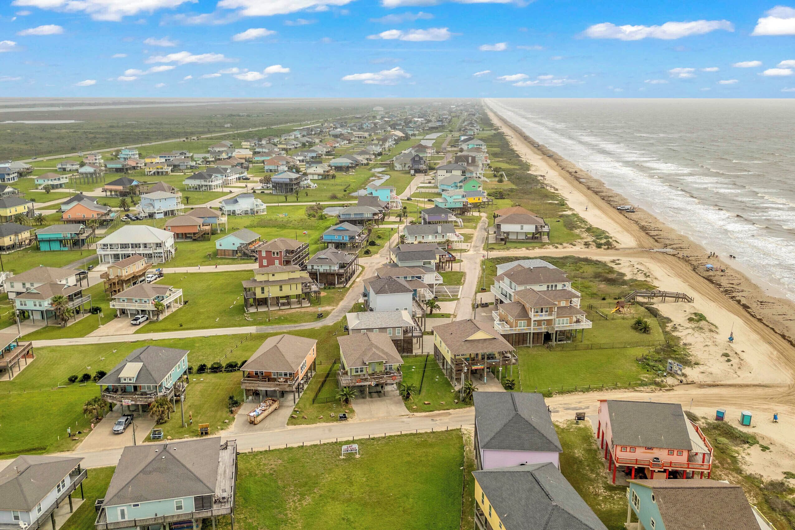 A coastal residential area with houses, a beach, and a clear sky.