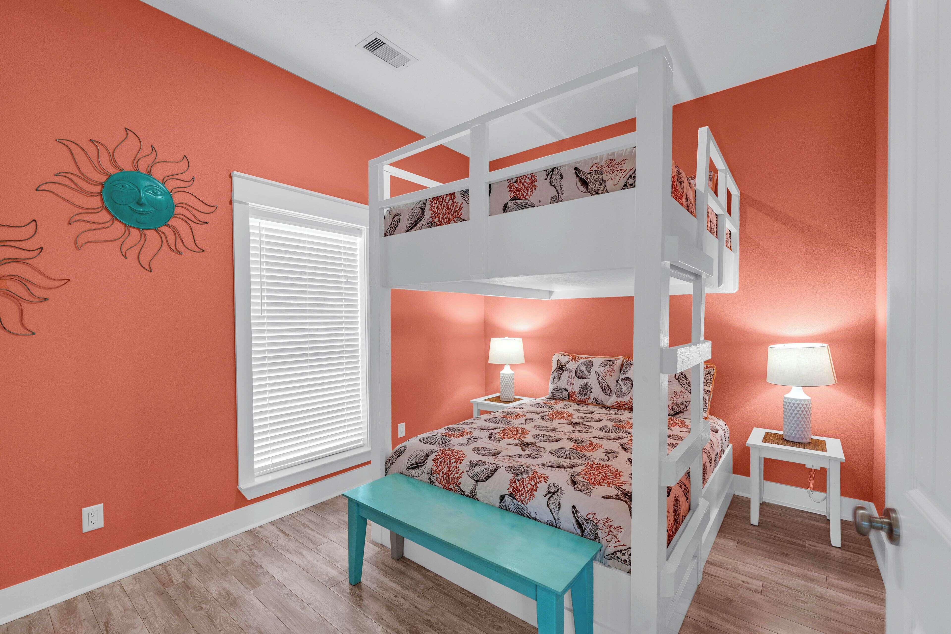 Une chambre avec un lit superposé, une fenêtre, un banc et une lampe fixée au mur.