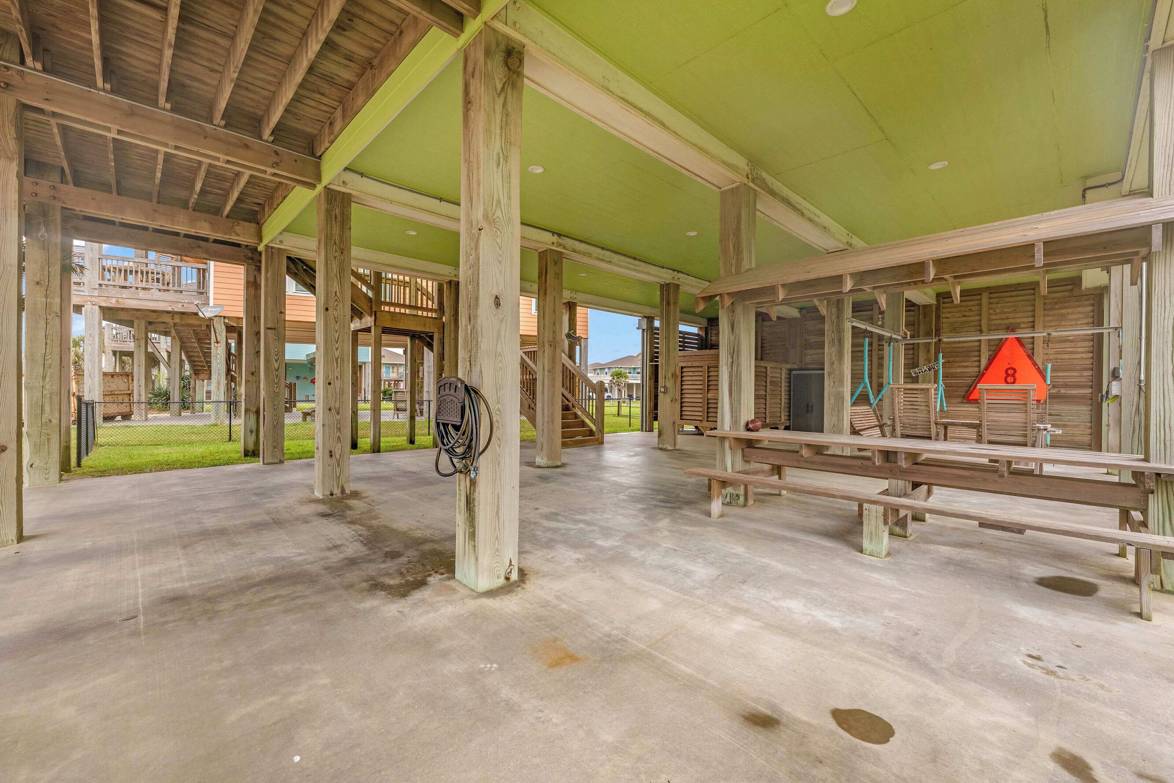 An indoor covered area with wooden beams, concrete flooring, and a green ceiling.